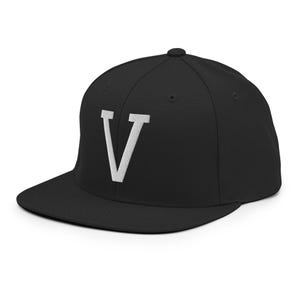 Könnte beinhalten: Schwarze Baseballkappe mit flachem Schirm. Auf der Kappe ist ein weiß gestickter Buchstabe "V" auf der Vorderseite zu sehen. Der Hut ist ein klassischer Stil, geeignet für Freizeitkleidung.