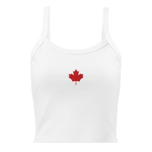 May include: White crop top with thin straps and a red maple leaf emblem. The top is a casual style, suitable for warm weather. The maple leaf is centered on the chest.