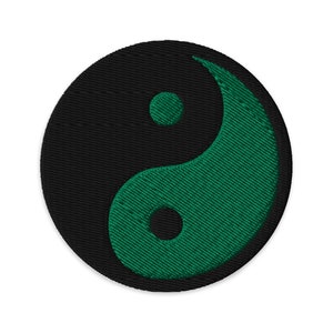 Pode incluir: Um símbolo yin yang preto e verde bordado em um remendo circular.