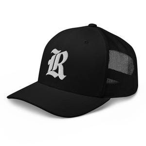 Pode incluir: Boné de caminhoneiro preto com a letra "R" branca bordada em uma fonte estilizada. O boné apresenta uma aba curva e uma parte traseira de malha. Um acessório clássico para uso casual.