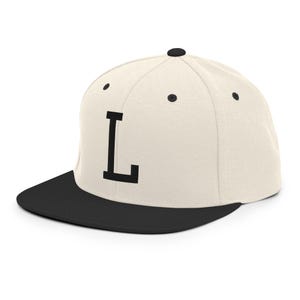 Könnte beinhalten: Cremefarbene Baseballkappe mit schwarzem Schirm und großem schwarzem Buchstaben "L" auf der Vorderseite. Die Kappe hat einen flachen Schirm und einen Knopf oben. Klassischer Stil.