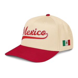 May include: A cream-colored baseball cap with a red brim and button. The word "Mexico" is embroidered in red script across the front. A small Mexican flag is embroidered on the side.
