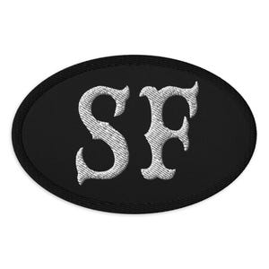 Peut inclure: Écusson ovale noir avec les lettres "SF" brodées en blanc.