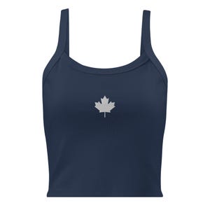 May include: A navy blue crop top with a white maple leaf emblem centered on the front. The top has thin straps and a scoop neckline. The fabric appears to be a soft, comfortable material.