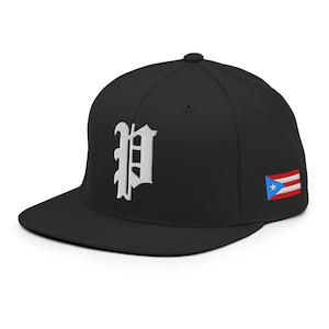 May include: Black baseball cap with a flat peak. The cap has a white embroidered letter "P" in an old English font on the front. The Puerto Rican flag is embroidered on the side.