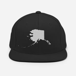 May include: A black and white embroidered baseball cap featuring the outline of the state of Alaska.