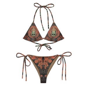May include: A black and orange bikini with a tie-side bottom. The bikini top is a triangle style with a print of a Buddha face.