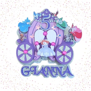 May include: Purple and silver glitter carriage cake topper with a princess figure, birds, and the number 5. The name "Gianna" is written below the carriage.