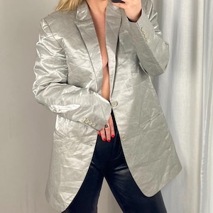 Może przedstawiać: Srebrny blazer o pomarszczonej fakturze. Blazer zapinany na jeden guzik, z długimi rękawami.