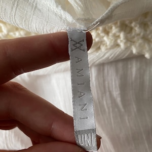 May include: White clothing tag with the text "UNI" and "XIAMIANI" printed on it.
