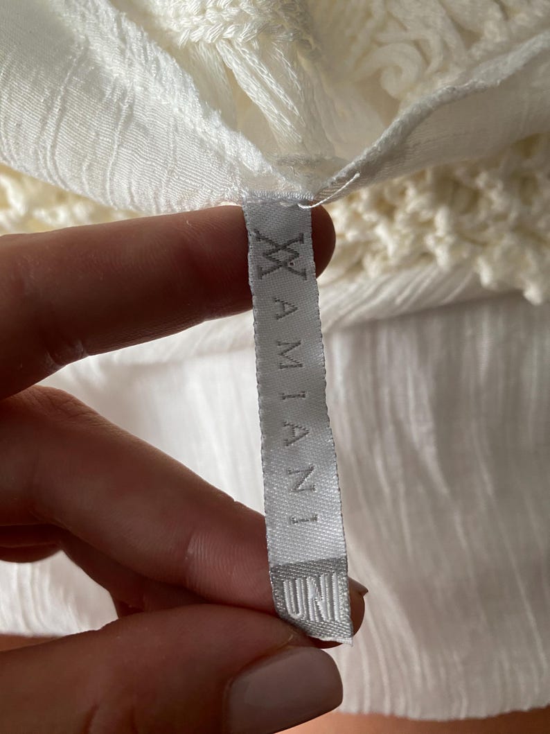 May include: White clothing tag with the text "UNI" and "XIAMIANI" printed on it.