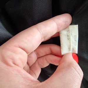 May include: A white fabric label with the text "SEVENTIES" printed in black. Below the text, it reads "Cotton 48% Polyamide 52%".