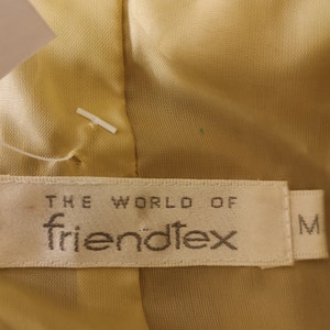 May include: A beige fabric label with the text "THE WORLD OF friend&ouml;tex" and the letter "M" in the bottom right corner.