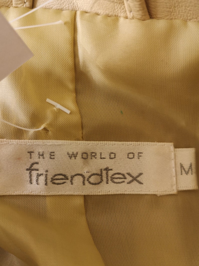 May include: A beige fabric label with the text "THE WORLD OF friend&ouml;tex" and the letter "M" in the bottom right corner.