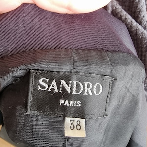 May include: A black Sandro Paris label with white text and a size 38 tag.