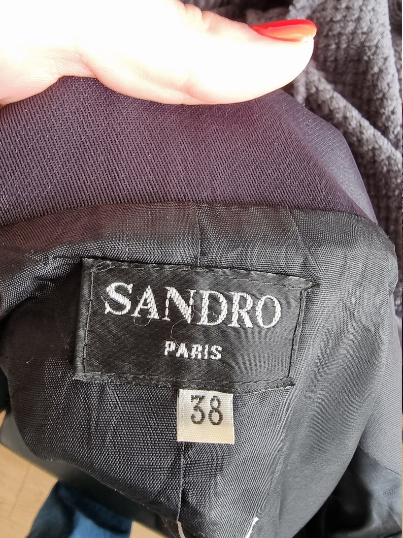 May include: A black Sandro Paris label with white text and a size 38 tag.