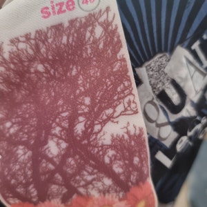 May include: A white tag with pink text that reads "size 40" in a circle. The tag has a floral pattern with pink flowers and a brown tree design.