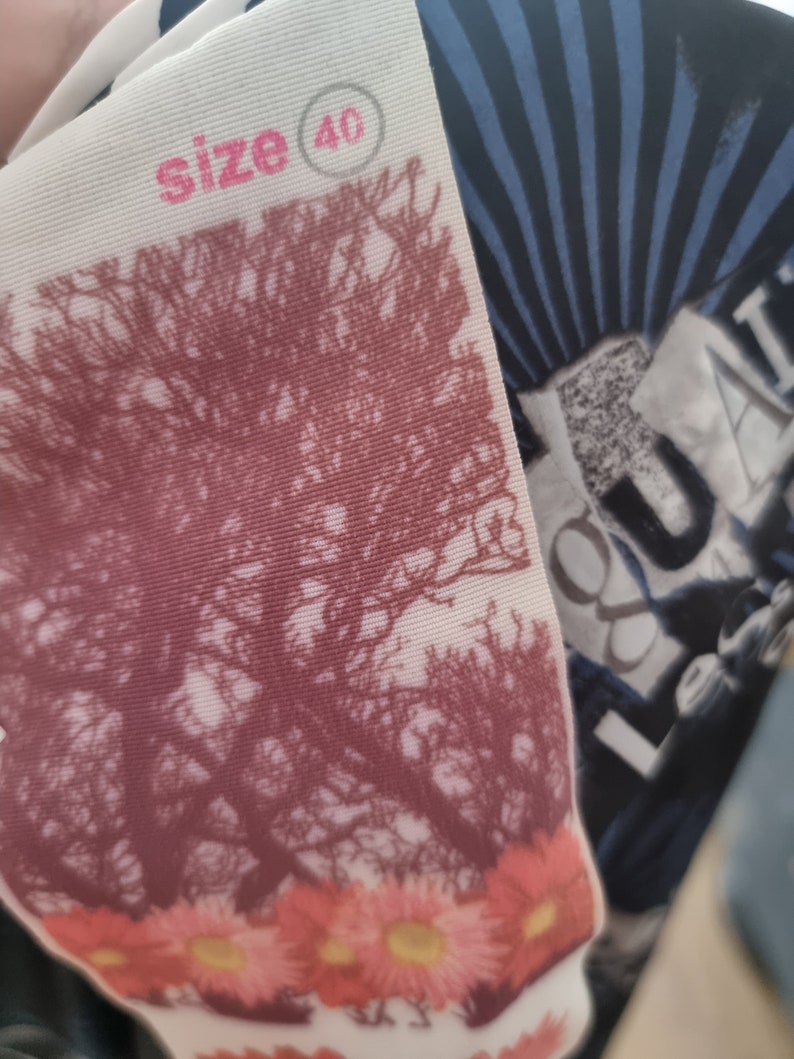 May include: A white tag with pink text that reads "size 40" in a circle. The tag has a floral pattern with pink flowers and a brown tree design.