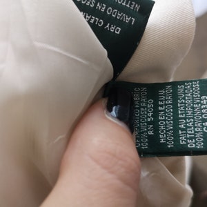 May include: A green fabric label with white text detailing the fabric content and origin of the garment. The label reads "Of imported fabric 100% viscose rayon RN 54050 Hecho en E.E.U.U. 100% Viscoso rayon Fait au Etats-Unis de telas importadas 100% rayonne viscose CA 08349"