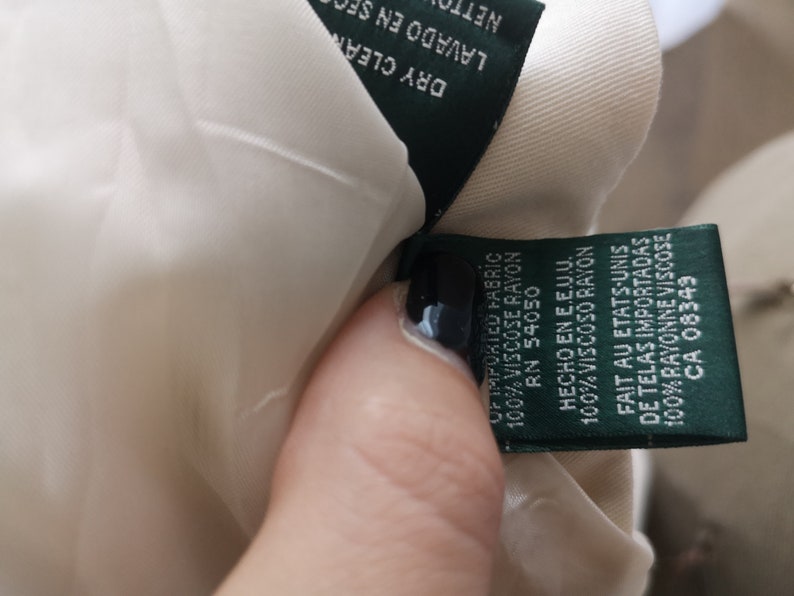 May include: A green fabric label with white text detailing the fabric content and origin of the garment. The label reads "Of imported fabric 100% viscose rayon RN 54050 Hecho en E.E.U.U. 100% Viscoso rayon Fait au Etats-Unis de telas importadas 100% rayonne viscose CA 08349"