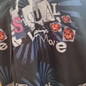 May include: Black fabric with a blue and white striped pattern. The fabric has a collage of images and text, including the words "Less is More" and "Signal".
