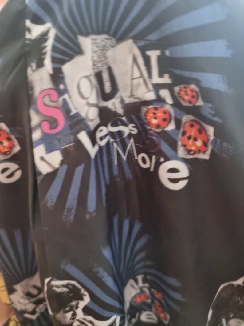 May include: Black fabric with a blue and white striped pattern. The fabric has a collage of images and text, including the words "Less is More" and "Signal".