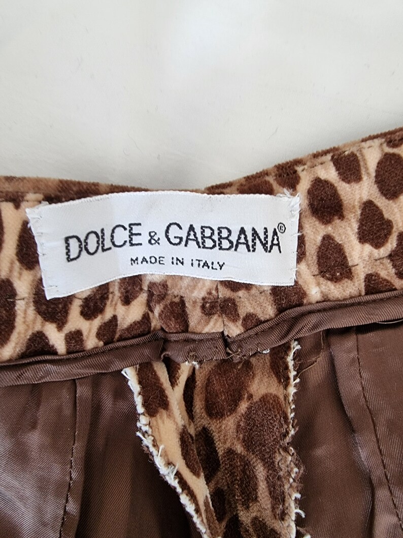 Puede incluir: Una tela de estampado de leopardo marr&oacute;n y beige con una etiqueta blanca que dice "DOLCE & GABBANA&reg; MADE IN ITALY".
