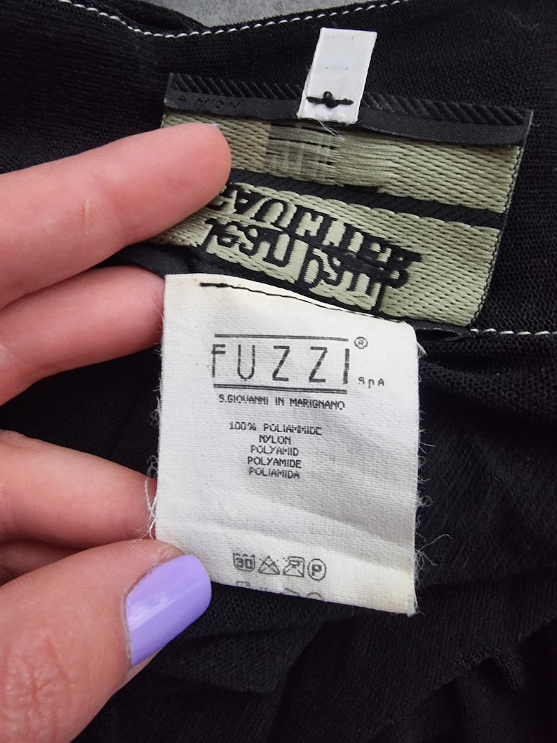 May include: White tag with black text that reads "FUZZI" and "S. GIOVANNI IN MARIGNANO SPA" with the text "100% POLIAMMIDE NYLON POLYAMID POLYAMIDE POLIAMIDA" below. The tag also has a care label with symbols for washing, ironing, and dry cleaning.