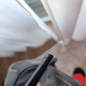 May include: Close-up of a black leather heeled shoe with a gold label that reads "Made in Brazil".