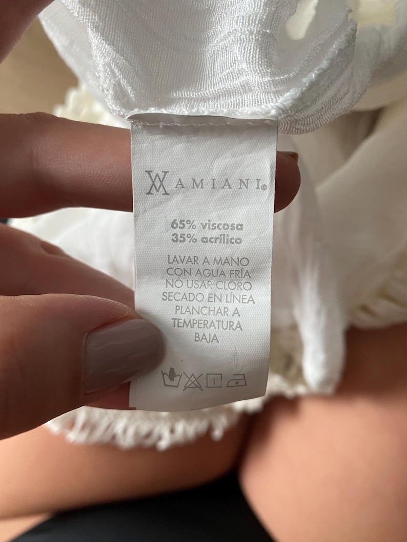 May include: White clothing care label with the brand name "MAMIANI."  The label includes the fabric composition: 65% viscose and 35% acrylic.  The care instructions are written in Spanish: "Lavar a mano con agua fr&iacute;a, no usar cloro, secado en l&iacute;nea, planchar a temperatura baja."