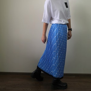 May include: A blue pleated skirt with a white geometric pattern. The skirt is midi length and has a black waistband.