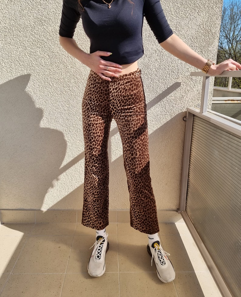 Puede incluir: Pantal&oacute;n de pierna ancha con estampado de leopardo marr&oacute;n y beige. El pantal&oacute;n se lleva con zapatillas blancas y calcetines blancos.