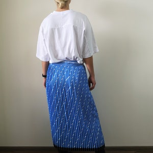 May include: A blue pleated skirt with a white geometric pattern. The skirt is midi length and has a black waistband.