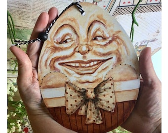 Humpty Dumpty gigante y feliz en una caja de pastel de Alicia en el país de las maravillas. Retrato de Humpty Dumpty pintado a mano. Adorno original para colgar en el árbol.