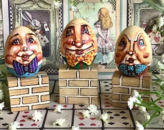 Humpty el pequeño en una pared. Humpty Dumpty en miniatura pintado a mano sobre un huevo de madera. Casa de muñecas Alicia en el país de las maravillas a través del espejo