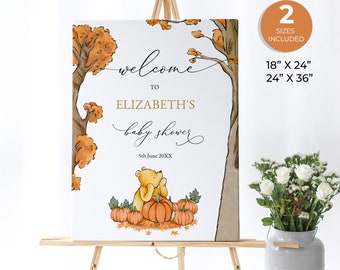 May include: A baby shower welcome sign on an easel. The sign features a Winnie the Pooh illustration with pumpkins and autumn leaves. Text includes "Welcome to Elizabeth's baby shower" and the date. Two size options are listed: 18" x 24" and 24" x 36".