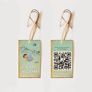 Może przedstawiać: Dwie prostokątne zawieszki rejestru prezentów o wyglądzie vintage. Jedna zawieszka przedstawia dziecko w niebieskiej kołysce, napisy "Gift Registry" i kwiatowy wzór. Druga zawieszka ma kod QR i napis "Scan Here". Obie mają wstążkę.