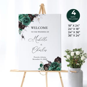 May include: A wedding welcome sign with a spooky Halloween theme. The sign features a black spider, green and burgundy floral accents, and the text "Welcome to the wedding of Michelle & Charles, Prescott, Arizona, November 15, 20XX".