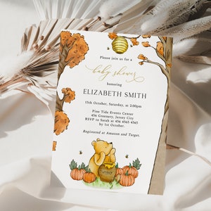 May include: Baby shower invitation featuring a watercolor illustration of Winnie the Pooh with pumpkins and a honey pot. The invitation includes event details, such as the date, time, and location, with the text "baby shower" in elegant script.