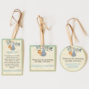 May include: Three baby shower favor tags with blue and green colors. The tags feature a baby in a blue and white bunting with birds on a branch. The text on the tags reads "Thank you for showering our baby with love. Samantha & Matthew".