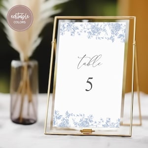 May include: A white table number card with a blue floral design and the text "Table 5" in black.