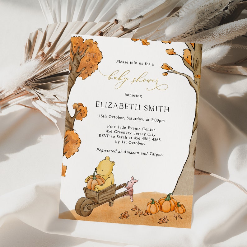 May include: Baby shower invitation featuring a watercolor illustration with Winnie the Pooh characters. The design includes a bear pushing a wheelbarrow with a pumpkin, a pig, and pumpkins. The invitation text is in gold script and includes event details.