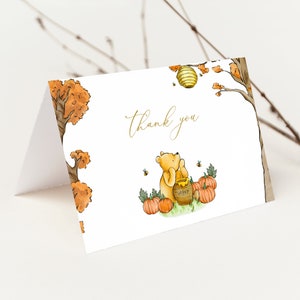 May include: A folded greeting card with a watercolor illustration of Winnie the Pooh with a honey pot and pumpkins. The words "Thank you" are written in gold script. The card has a fall theme with trees and a beehive.