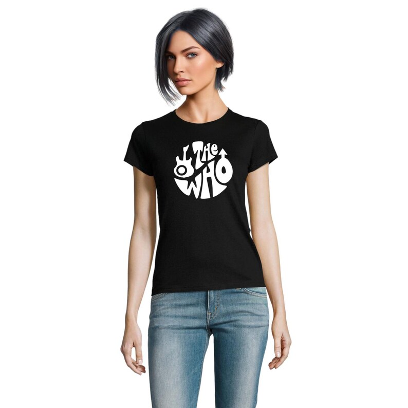 May include: Black t-shirt with a white circular design featuring the words "The Who" and a guitar. The top is a crew neck and is worn with blue jeans. The design is a classic music band logo.
