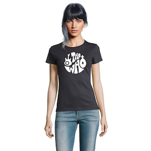 May include: A dark grey t-shirt with a white circular design featuring the band name "The Who" and musical instrument graphics. The shirt is short-sleeved and worn with blue jeans.