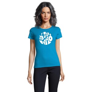 May include: A turquoise blue t-shirt with a white circular graphic featuring the text "The Who" and musical instrument illustrations. The shirt has short sleeves and a crew neck.