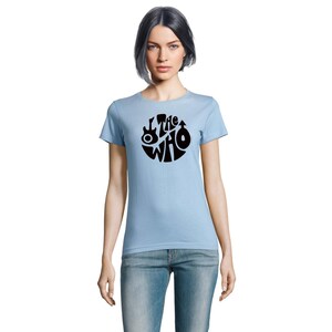 May include: Pale blue t-shirt with a black circular design featuring the words "The Who" and musical instrument graphics. The shirt is made of a soft fabric and has short sleeves.