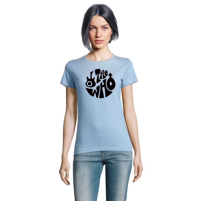 May include: Pale blue t-shirt with a black circular design featuring the words "The Who" and musical instrument graphics. The shirt is made of a soft fabric and has short sleeves.