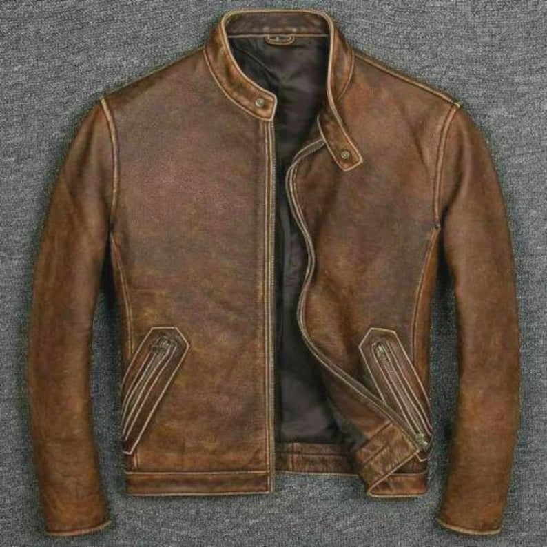 May include: A brown leather jacket with a stand-up collar and a zipper closure. The jacket has two zippered pockets and a distressed finish, giving it a vintage look. The jacket is a classic style, suitable for various occasions.
