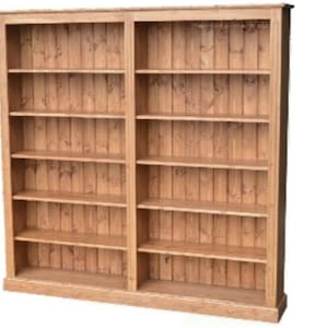 May include: A large, double wooden bookcase with multiple shelves. The bookcase is made of light-coloured wood with a natural finish. It has a rectangular shape and is designed for storing books and other items.